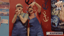 two people pose in front of a wall with anchors on it