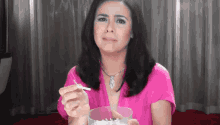 a woman in a pink shirt holds a cigarette in her hand