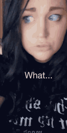 a woman with blue eyes is wearing a black shirt that says ' what ' on it