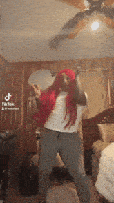 a woman with red hair is dancing in a bedroom with a tiktok logo on the ceiling