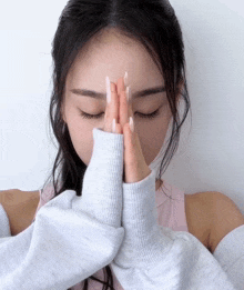 a woman with her eyes closed and her hands folded on her forehead