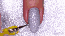 a close up of a person 's nails being painted with a yellow tool .
