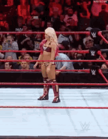 a female wrestler is standing in a wrestling ring .