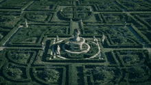 an aerial view of a garden with statues and a fountain in the middle