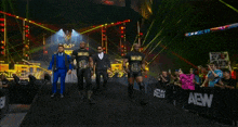 a group of men are walking down a wrestling ring with a sign that says aew