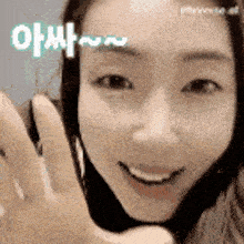 a close up of a woman 's face with a hand waving in front of her .