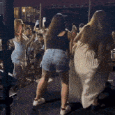 a group of women are dancing on a stage and one of them is wearing shorts