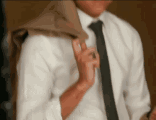 a man in a white shirt and tie holds his jacket over his shoulder