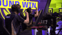 a man wearing headphones is sitting in front of a yellow sign that says win