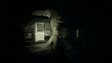a person in a hooded jacket is standing in a dark room