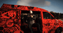a man in a mask stands in front of a red van with a sticker on the side that says ' apocalypse '