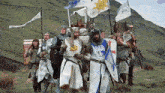 a group of knights are walking in a field with flags