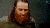 a man with a beard and long hair is wearing a jacket .