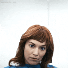 a woman with red hair is making a funny face in front of a white wall