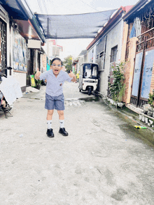 a little boy is giving a thumbs up in a narrow alleyway