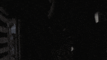 a person is standing in a dark room with a striped wall behind them