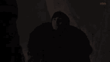 bran stark from game of thrones is wearing a fur coat in the dark .