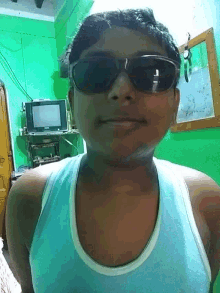 a man wearing sunglasses and a tank top is smiling