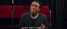 a man in a gray sweater says my emotions in front of red chairs