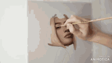 a person is painting a woman 's face with a brush