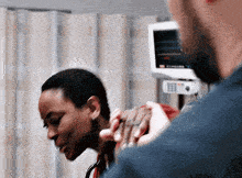 a man is holding a woman 's hand in a hospital room in front of a monitor .