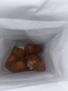 a bag of fried chicken wings is sitting on a white surface