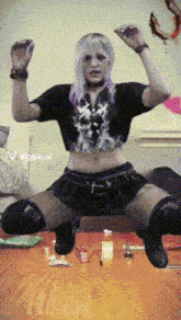 a woman with purple hair is kneeling on a wooden table