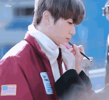 a person is applying lipstick to a young man 's lips .