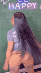 a woman with long hair is dancing in front of a sign that says happy