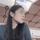 a woman wearing a cat ear headband looks to the side in front of a striped ceiling