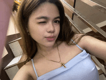 a woman wearing a blue top and a gold necklace with a cross on it