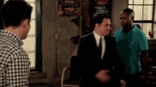a man in a blue shirt is standing next to a man in a black suit