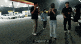 a group of people are standing in front of a gas station with a sign that says dc