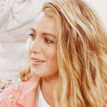 a woman wearing a pink jacket with pearls on it
