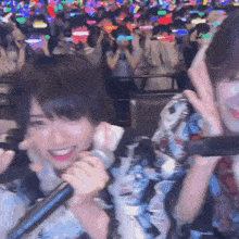 a woman singing into a microphone with a crowd behind her