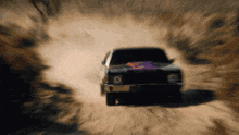 a car is driving down a dirt road with a lot of dust