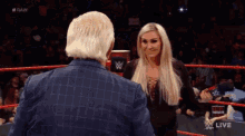 a man and a woman are standing in a wrestling ring and talking to each other .