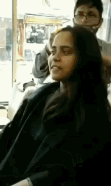 a woman is sitting in a chair getting her hair cut by a man wearing a mask .