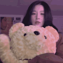 a woman is holding a teddy bear with a purple background