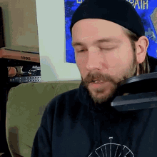a man with a beard wears a black hat and a black shirt that says death on it