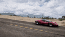 a red sports car driving down a desert road