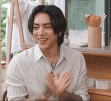 a man wearing a striped shirt is smiling and clapping his hands