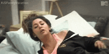 a woman is laying in bed with her head on a pillow and making a funny face .