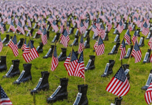 a field filled with american flags and boots with a name tag on them