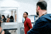 a woman in a red jacket is standing next to a man in a blue shirt in a hospital room .
