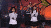 two women singing in front of a drum set made by tama