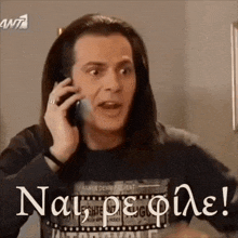 a man with long hair is talking on a cell phone while wearing a t-shirt that says ant