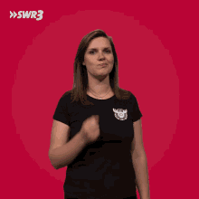 a woman in a black shirt is making a middle finger gesture in front of a swr3 logo
