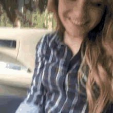 a girl in a plaid shirt is sitting in the back seat of a car .
