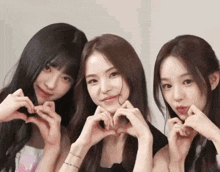 three women are making a heart shape with their hands